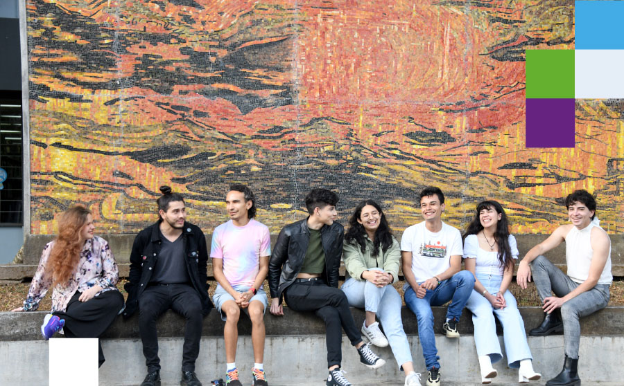 Grupo de 5 personas sentadas sobre un muro, sonriendo y teniendo una conversación